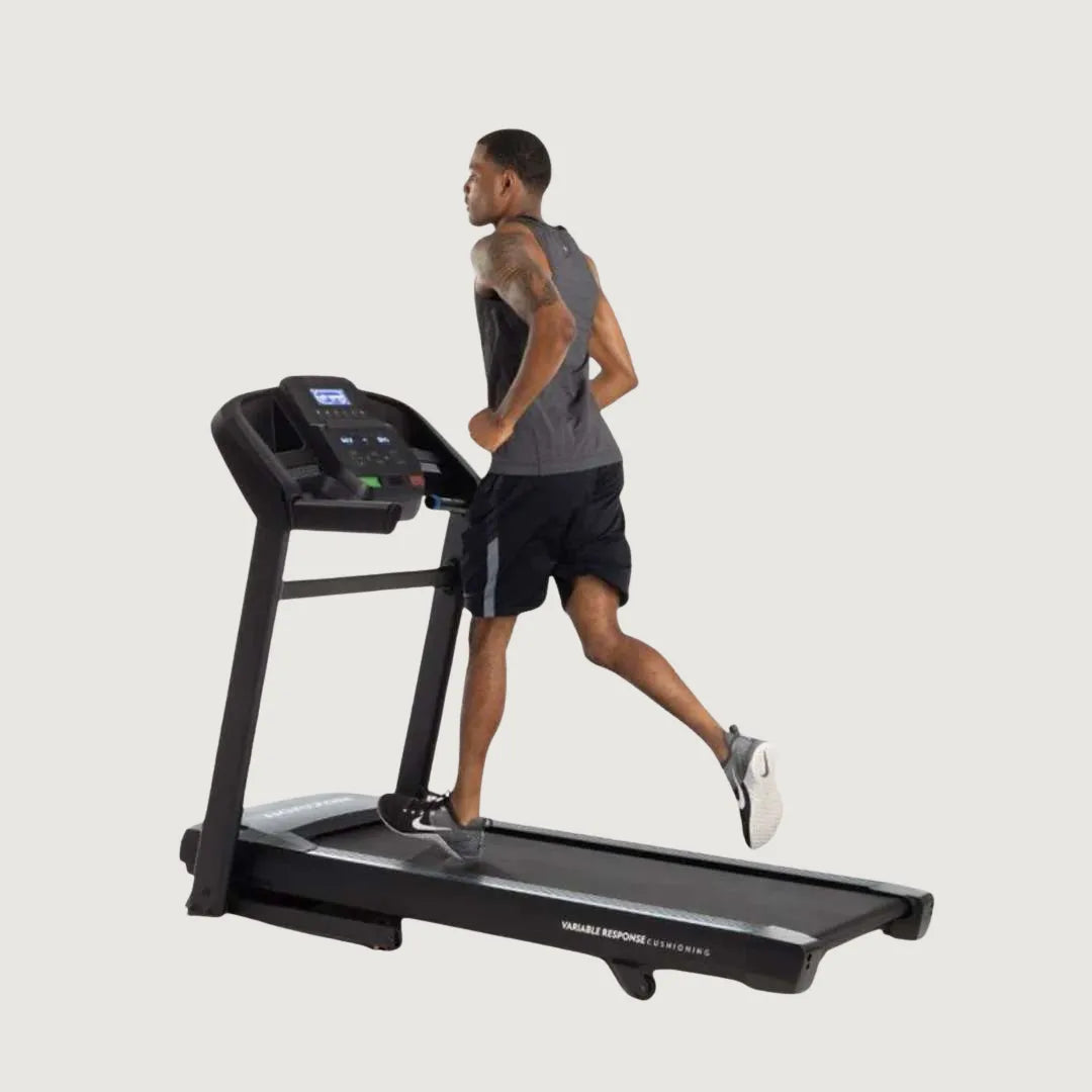 Man running on a Horizon treadmill with digital display and side handles.
