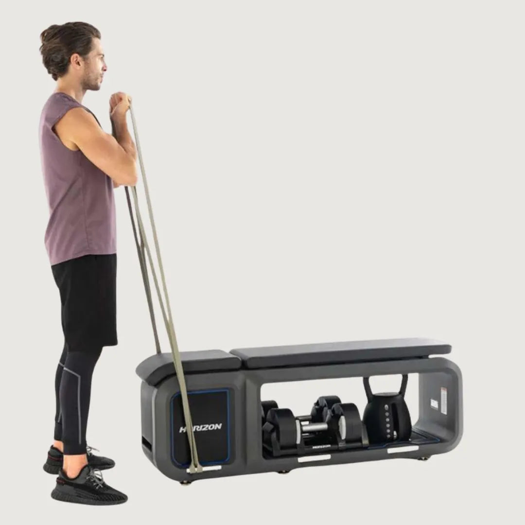 Man using resistance bands for upright rows while standing next to the Horizon workout bench.