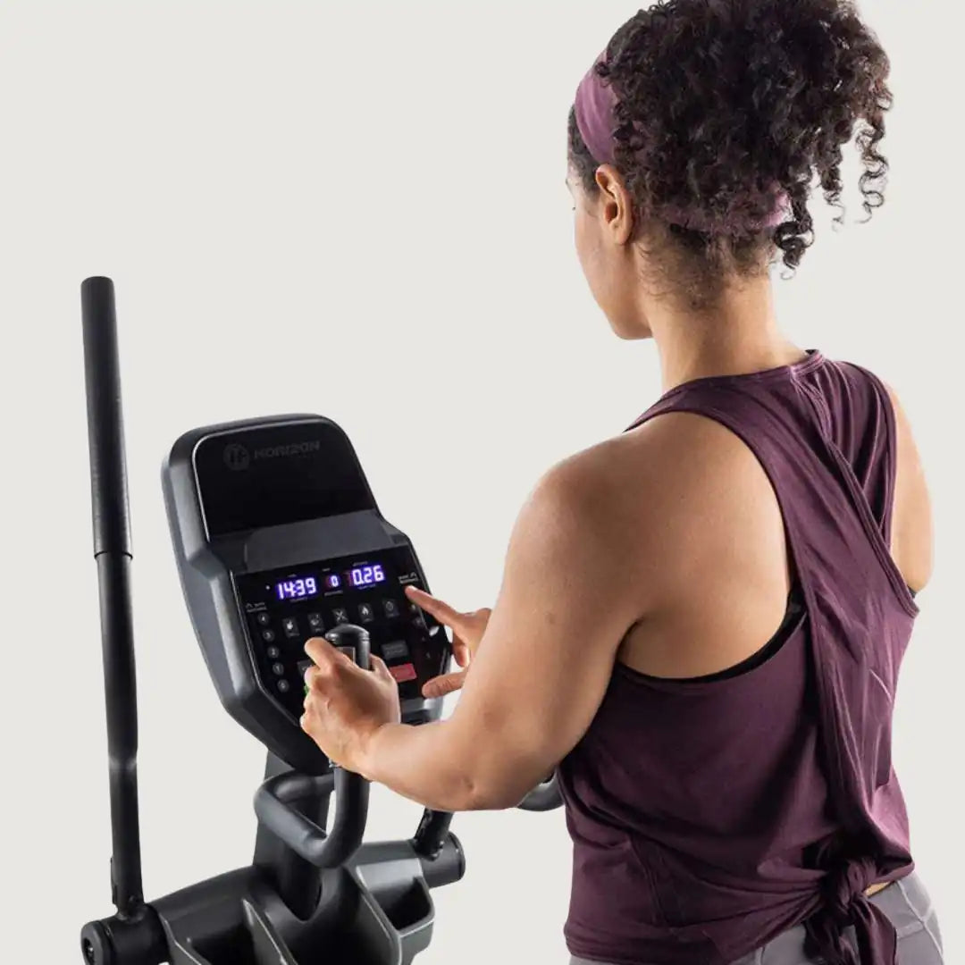 Woman adjusting settings on Horizon elliptical console during workout