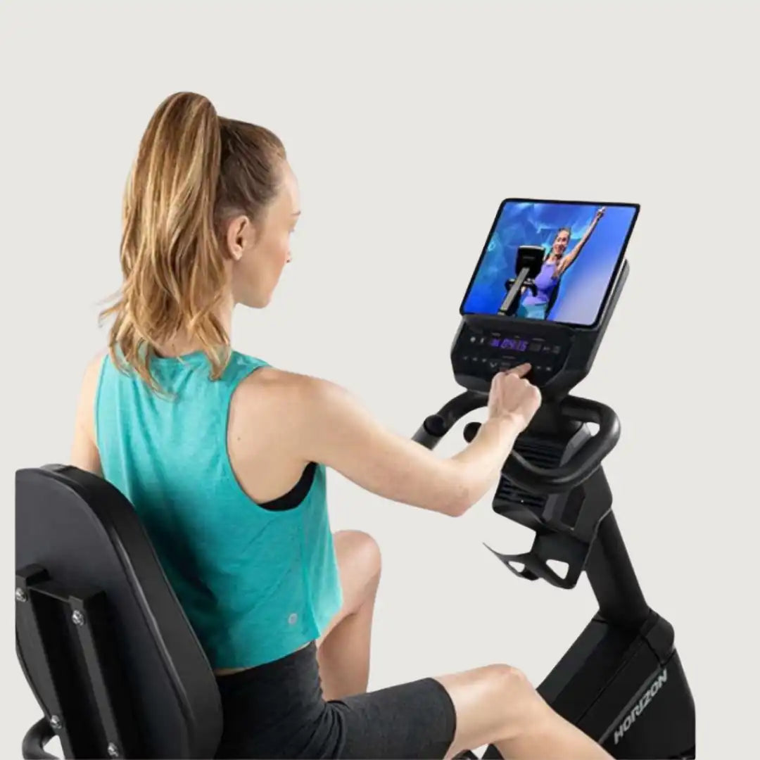 Woman using Horizon recumbent bike and navigating touchscreen display