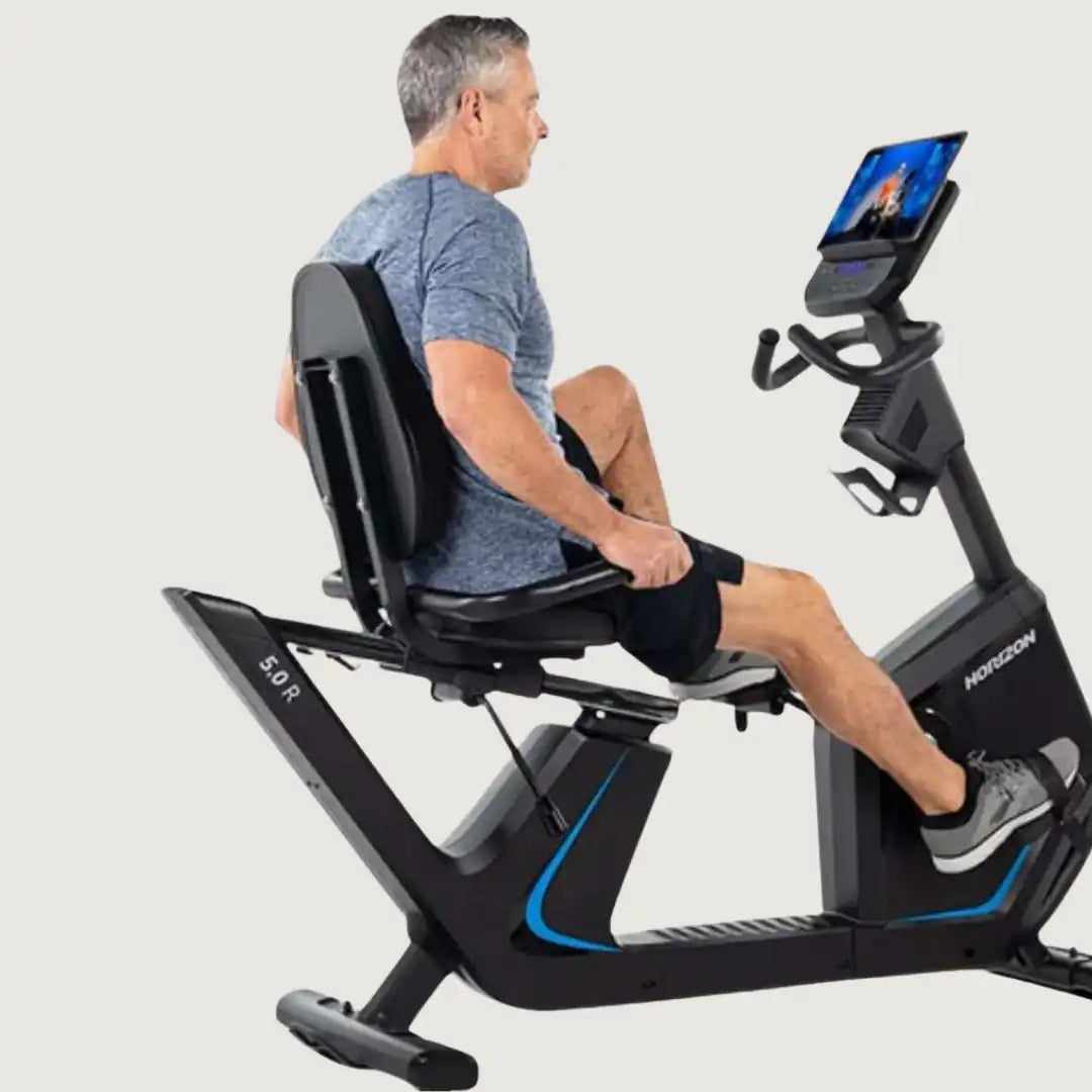 Man seated on Horizon recumbent bike watching a screen while pedaling