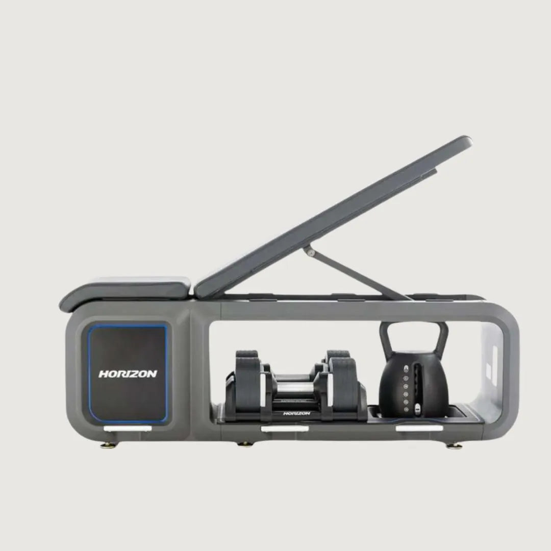 Horizon bench with lid open, displaying a compact storage system for adjustable dumbbells and a kettlebell.