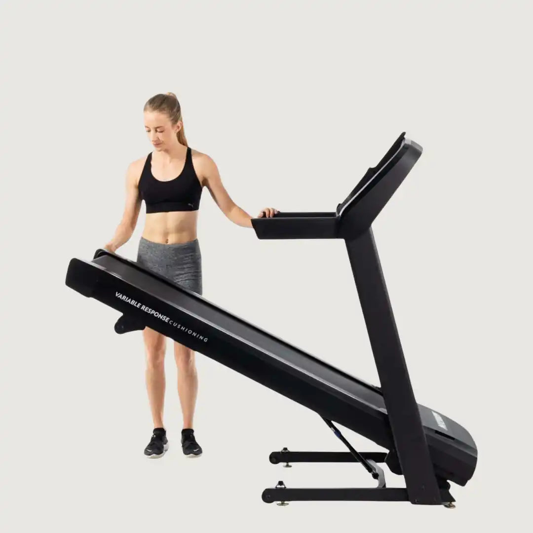 Woman folding the Horizon treadmill down for workout use