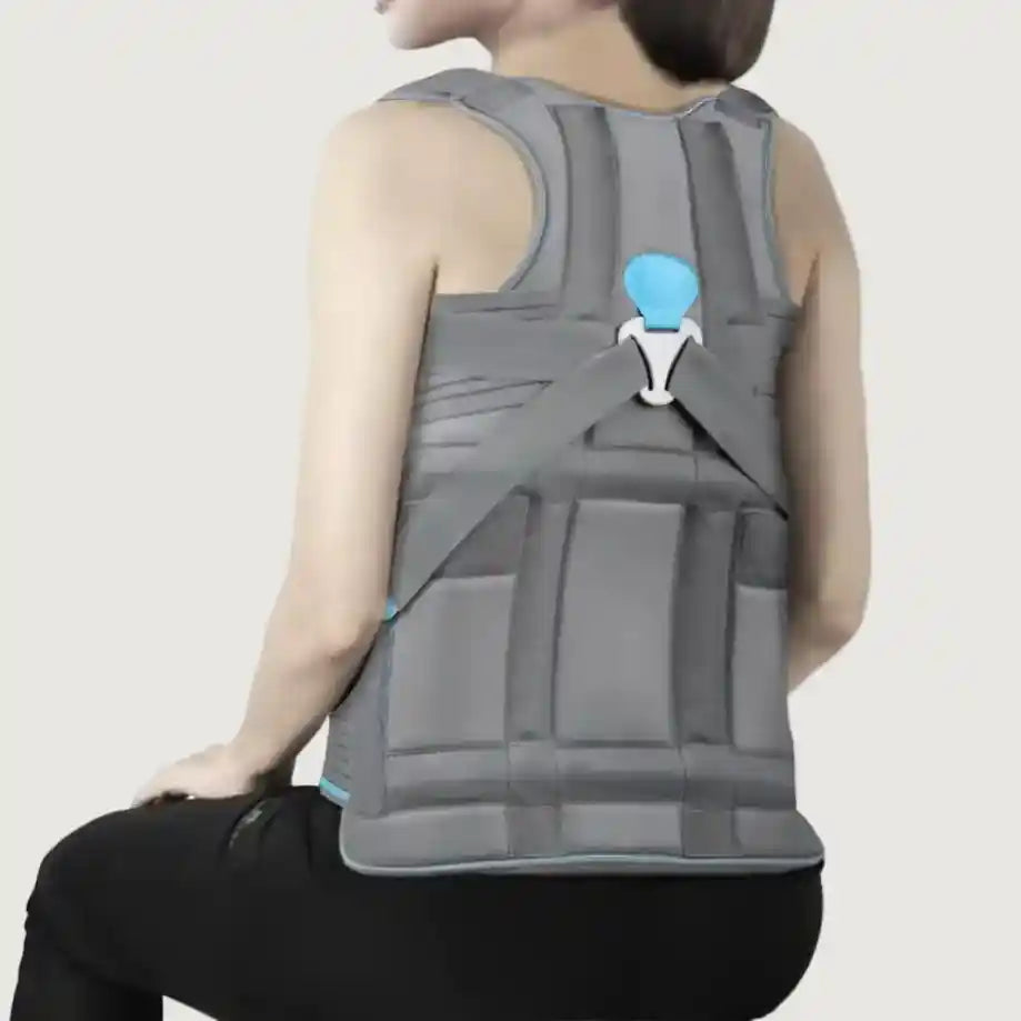 Person wearing a gray back brace with a blue indicator on a plain background