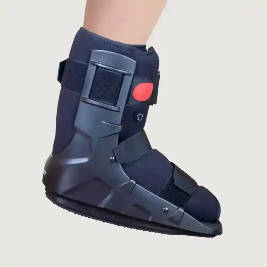 Navy blue ankle boot with a red button on a light gray background