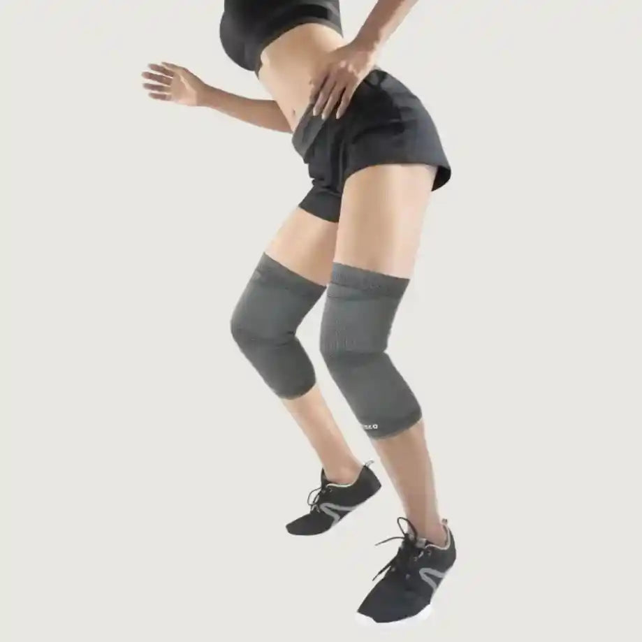 Person wearing gray knee sleeves on a plain background