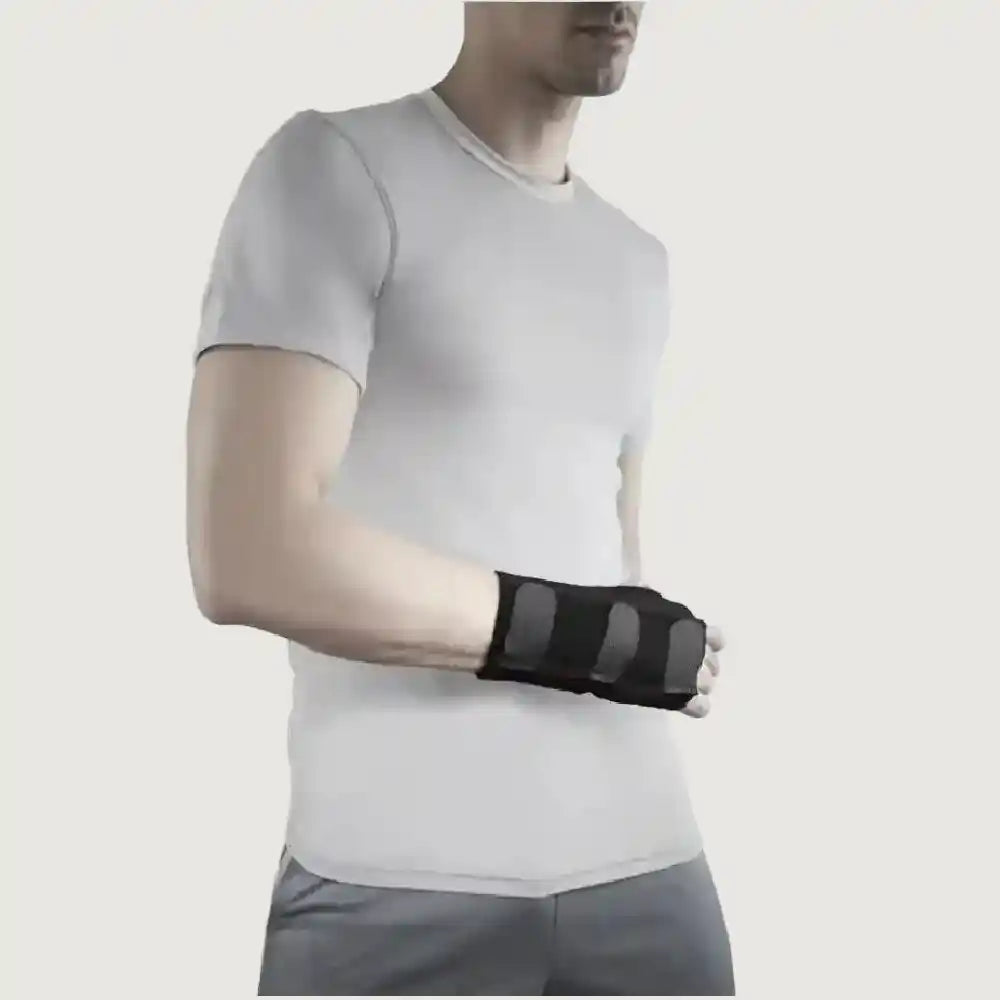 Person wearing a black wrist support on a plain background