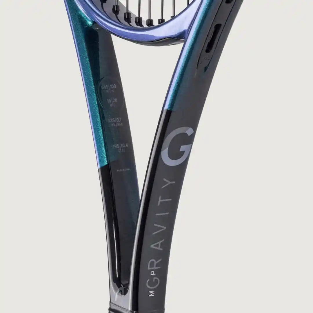 Close-up of a tennis racket frame showing the throat and upper racquet head, with a metallic teal-to-blue gradient and a black lower section featuring a large white 'G' and vertical 'M GRAVITY' branding, on a light gray background.