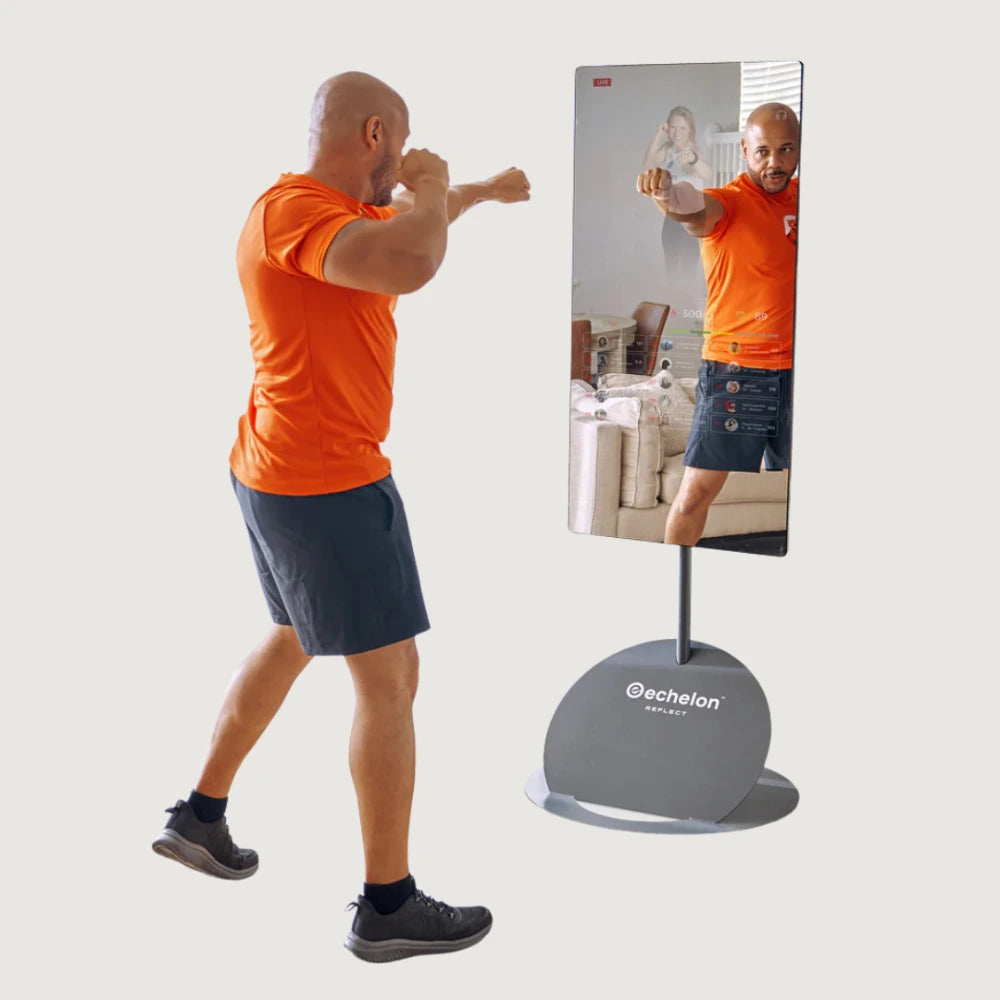 Person in orange shirt and blue shorts practicing boxing in front of a mirror with 'echelon' branding.