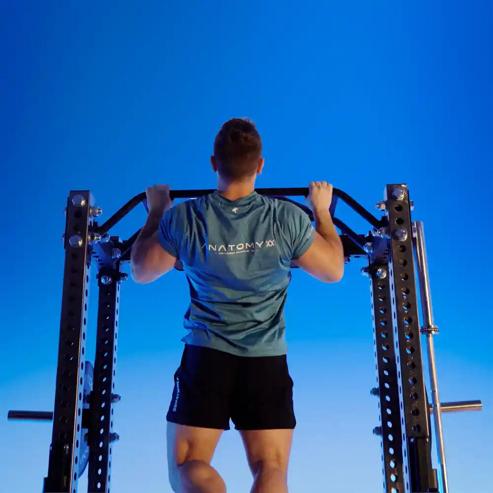 Person exercising on outdoor fitness equipment against a clear blue sky